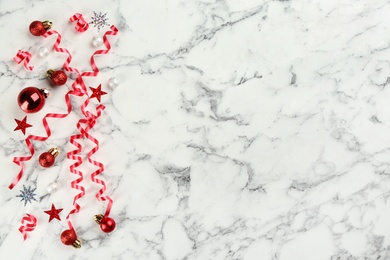 Red serpentine streamers and Christmas balls on white marble background, flat lay. Space for text