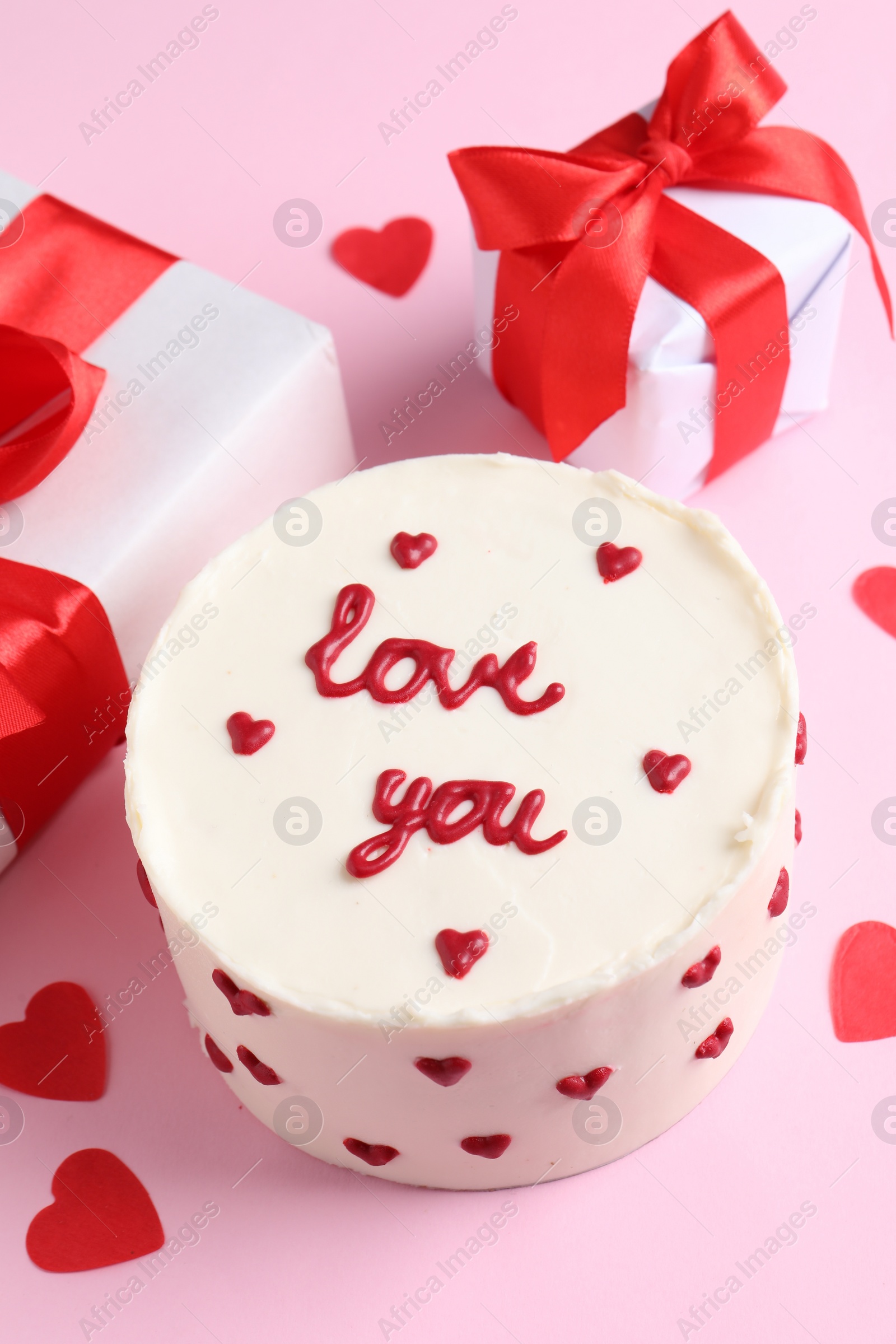 Photo of Bento cake with text Love You, gift boxes and paper hearts on pink table. St. Valentine's day surprise