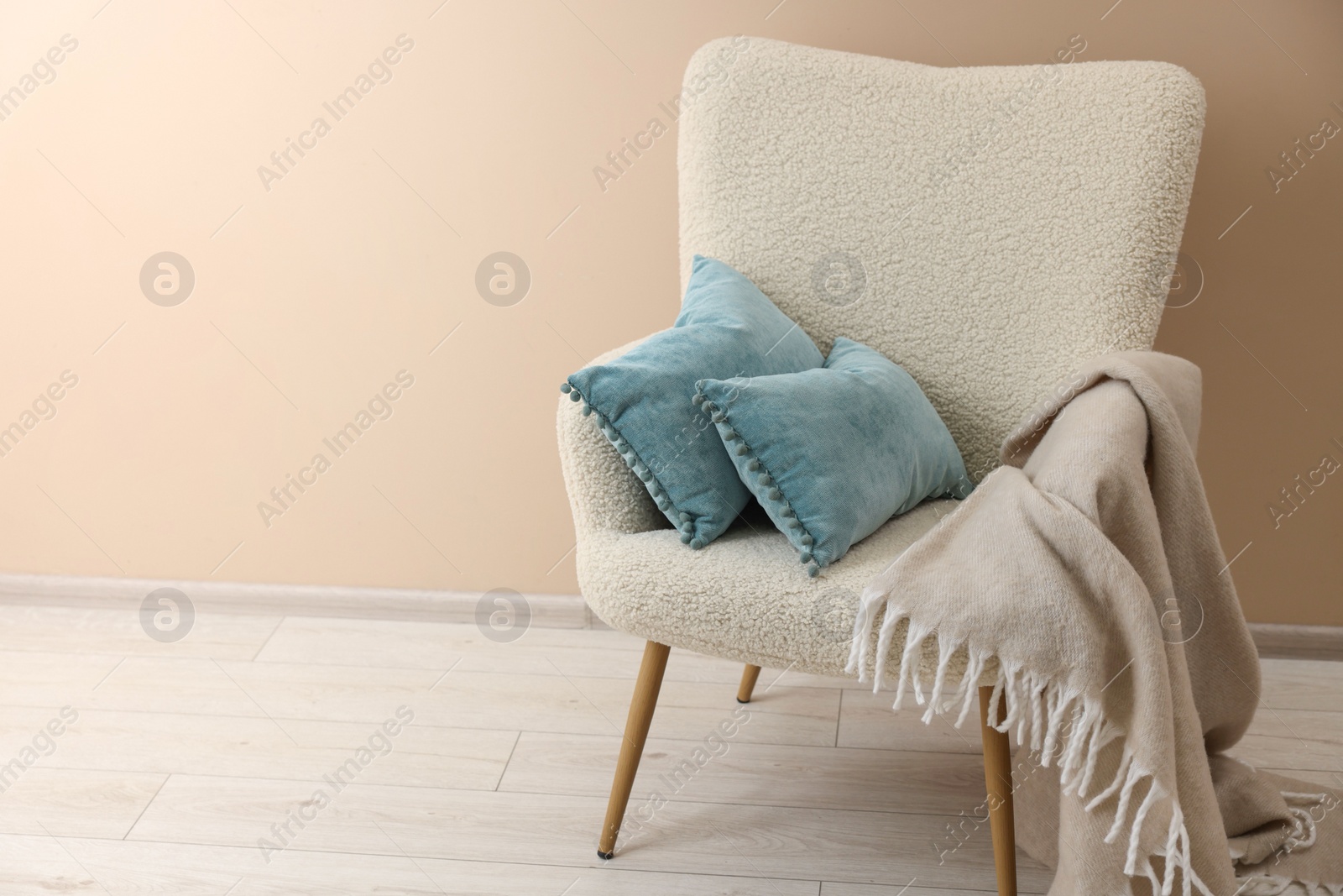 Photo of Soft blue pillows and blanket on armchair indoors. Space for text