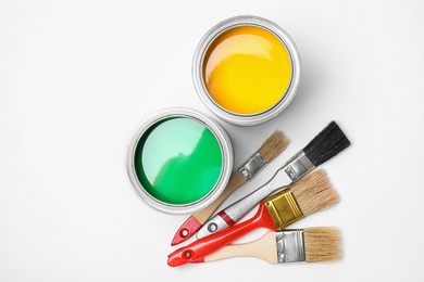 Open cans of paint and brushes on white background, top view