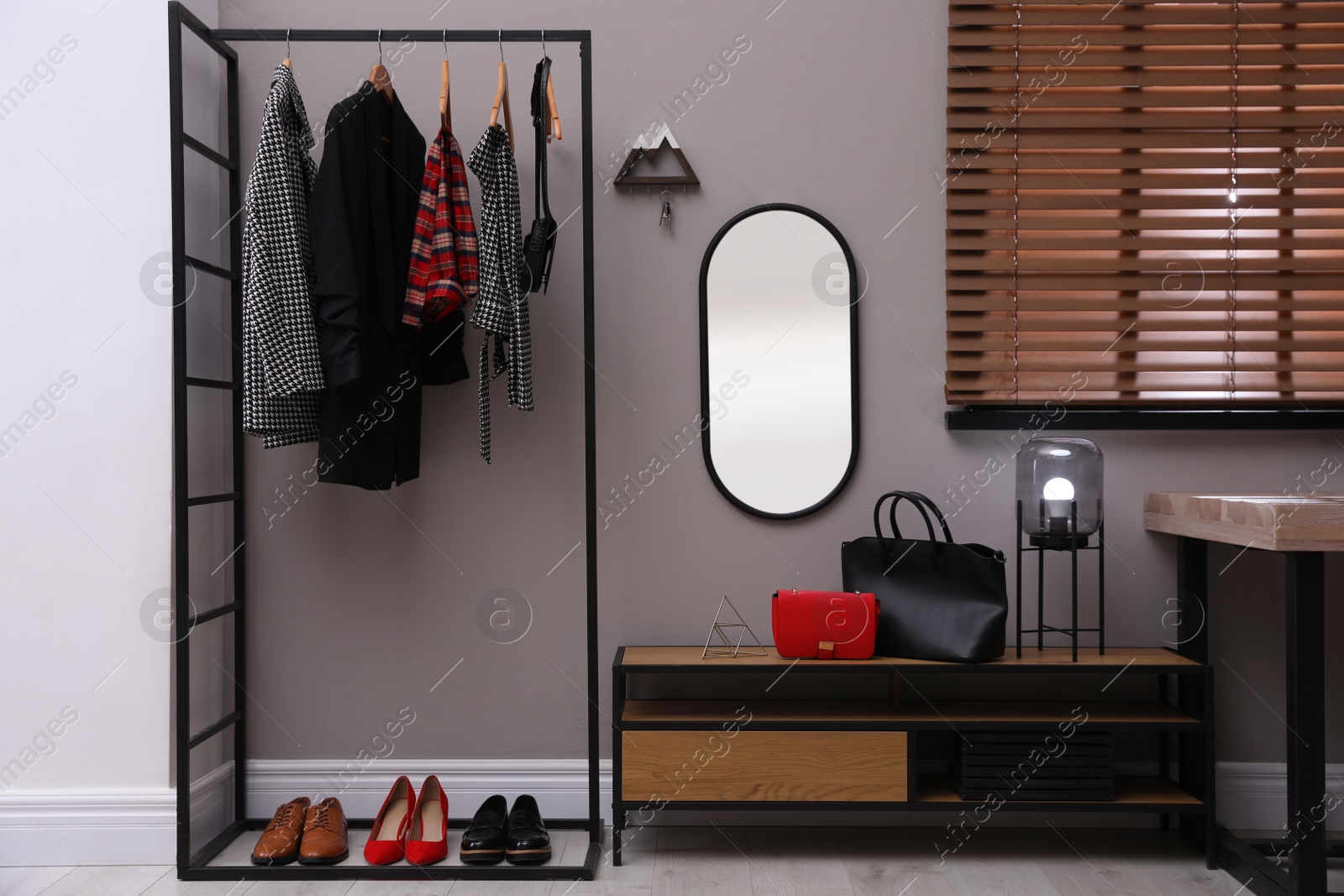 Photo of Modern hallway interior with stylish furniture, mirror and wooden hanger for keys on grey wall