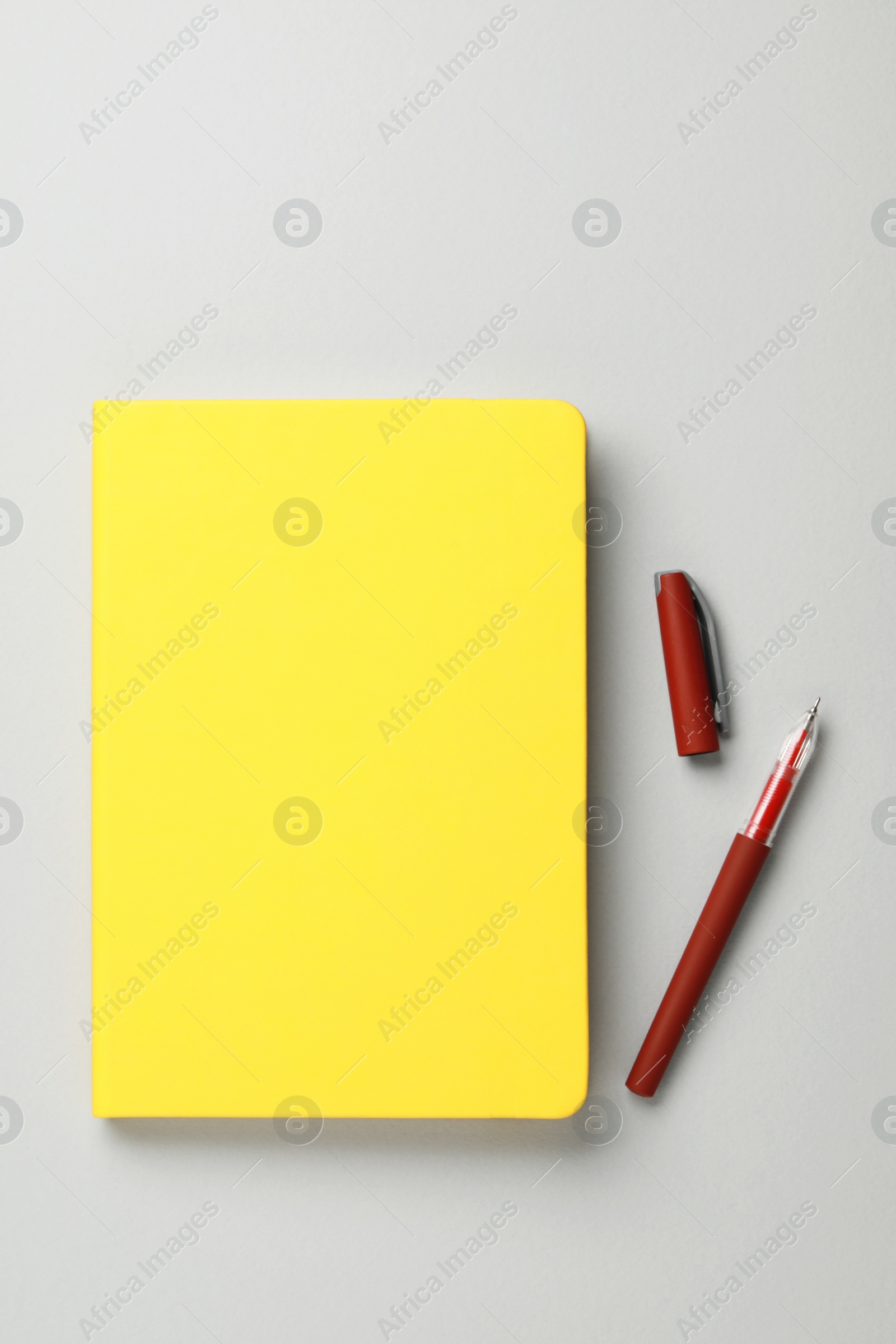 Photo of Yellow notebook and pen on gray background, flat lay