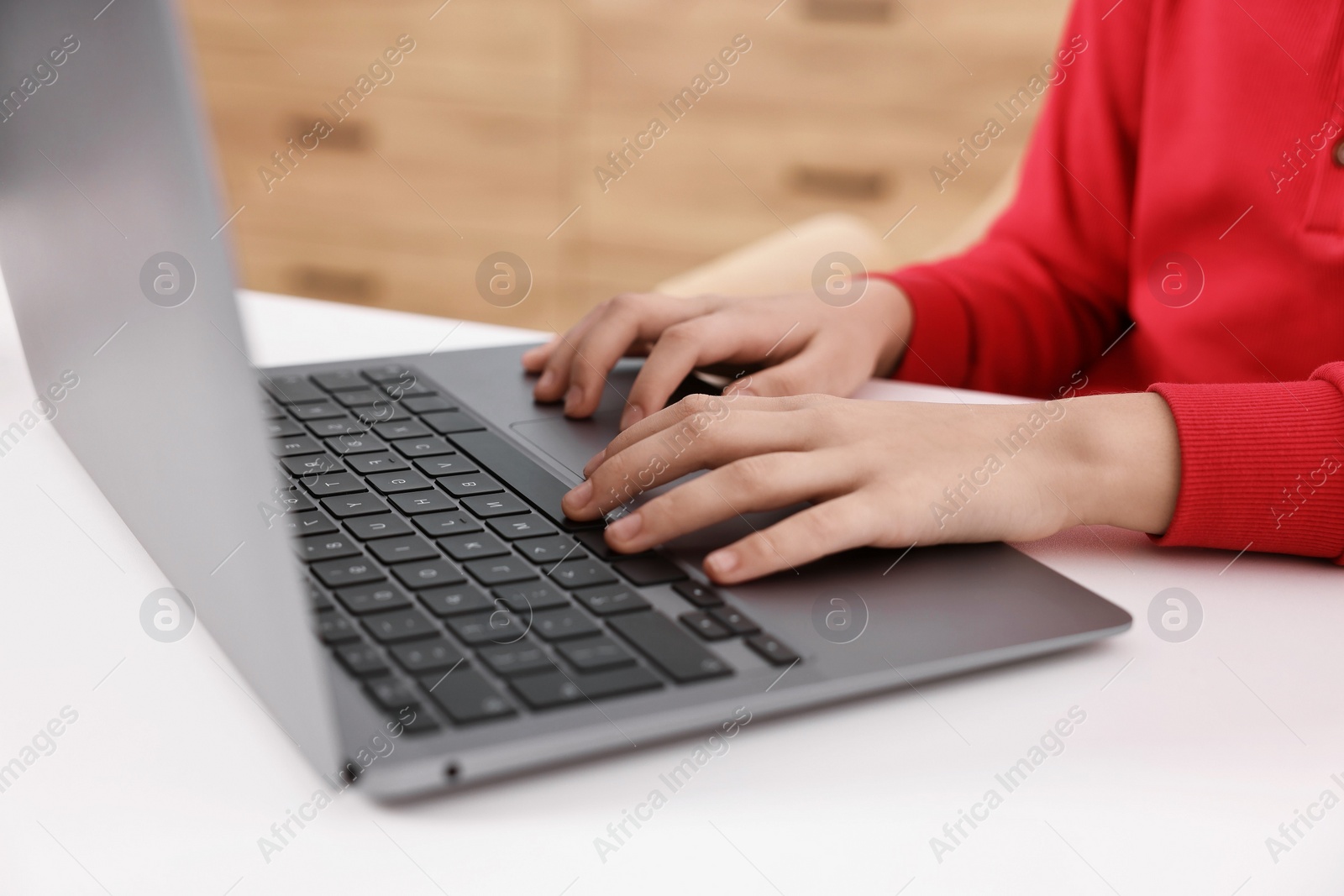 Photo of E-learning. Girl using laptop during online lesson at table indoors, closeup