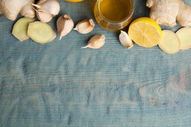 Photo of Fresh garlic and other natural cold remedies on light blue wooden table, flat lay. Space for text