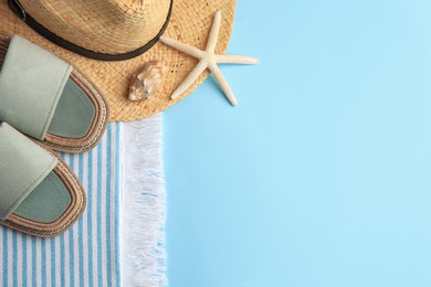 Flat lay composition with beach accessories on light blue background, space for text