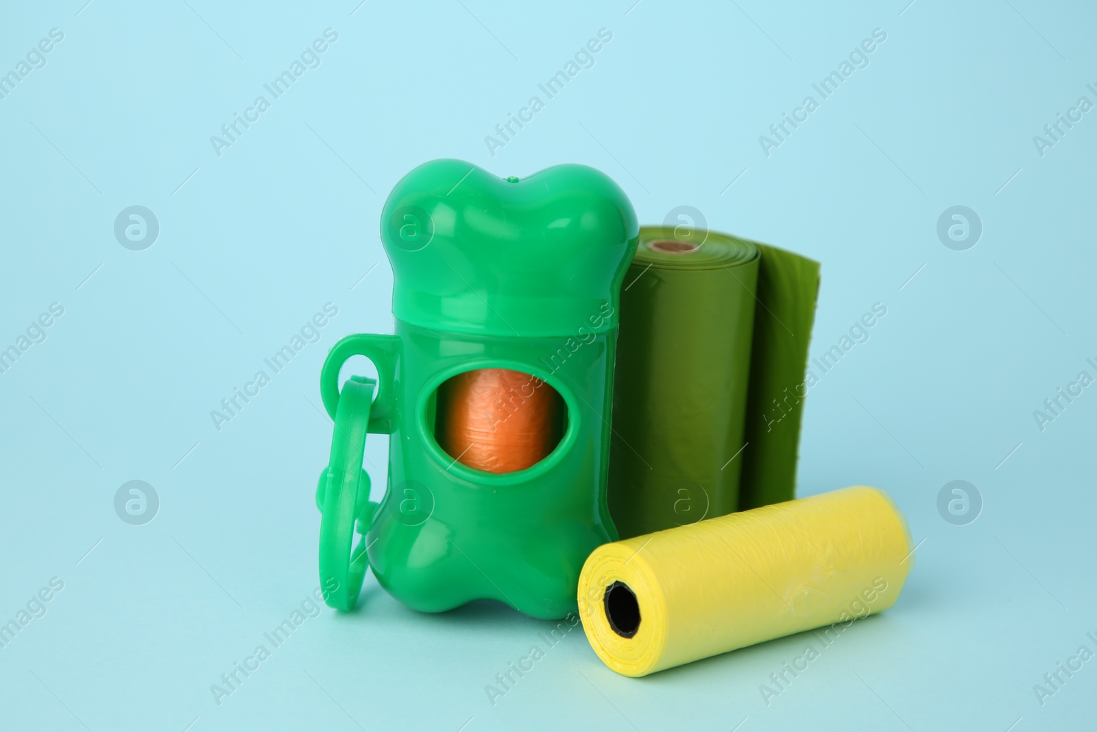 Photo of Dog waste bags and dispenser on light blue background