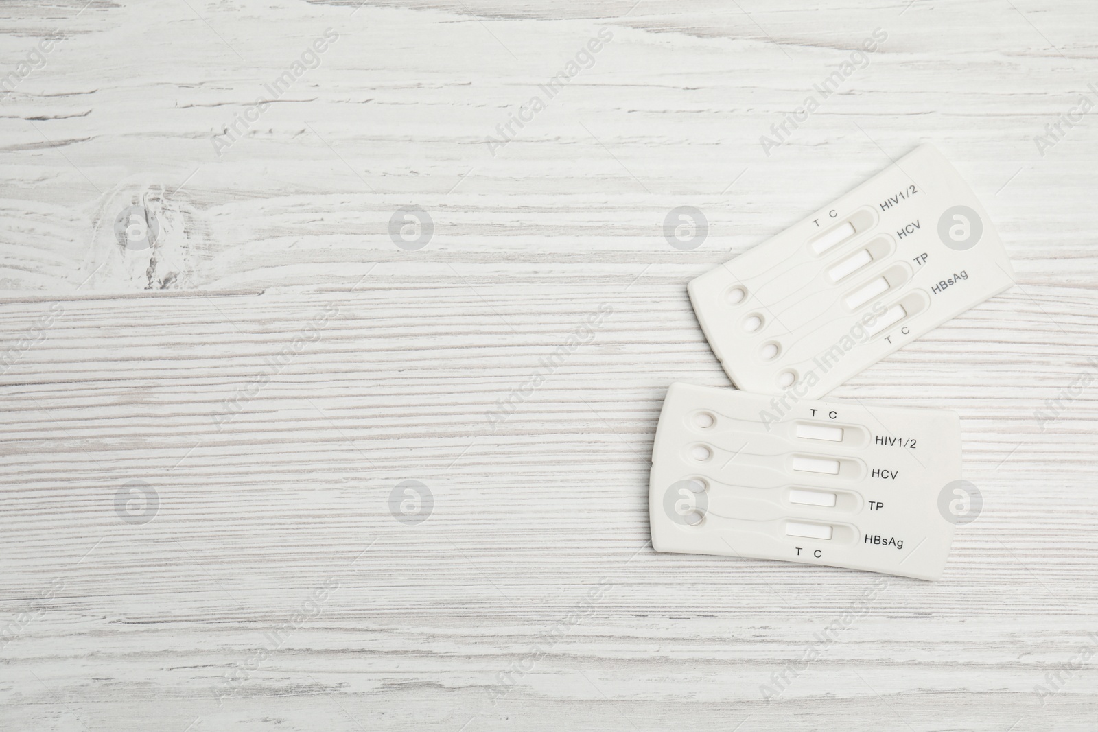 Photo of Two disposable express hepatitis tests on white wooden table, flat lay. Space for text