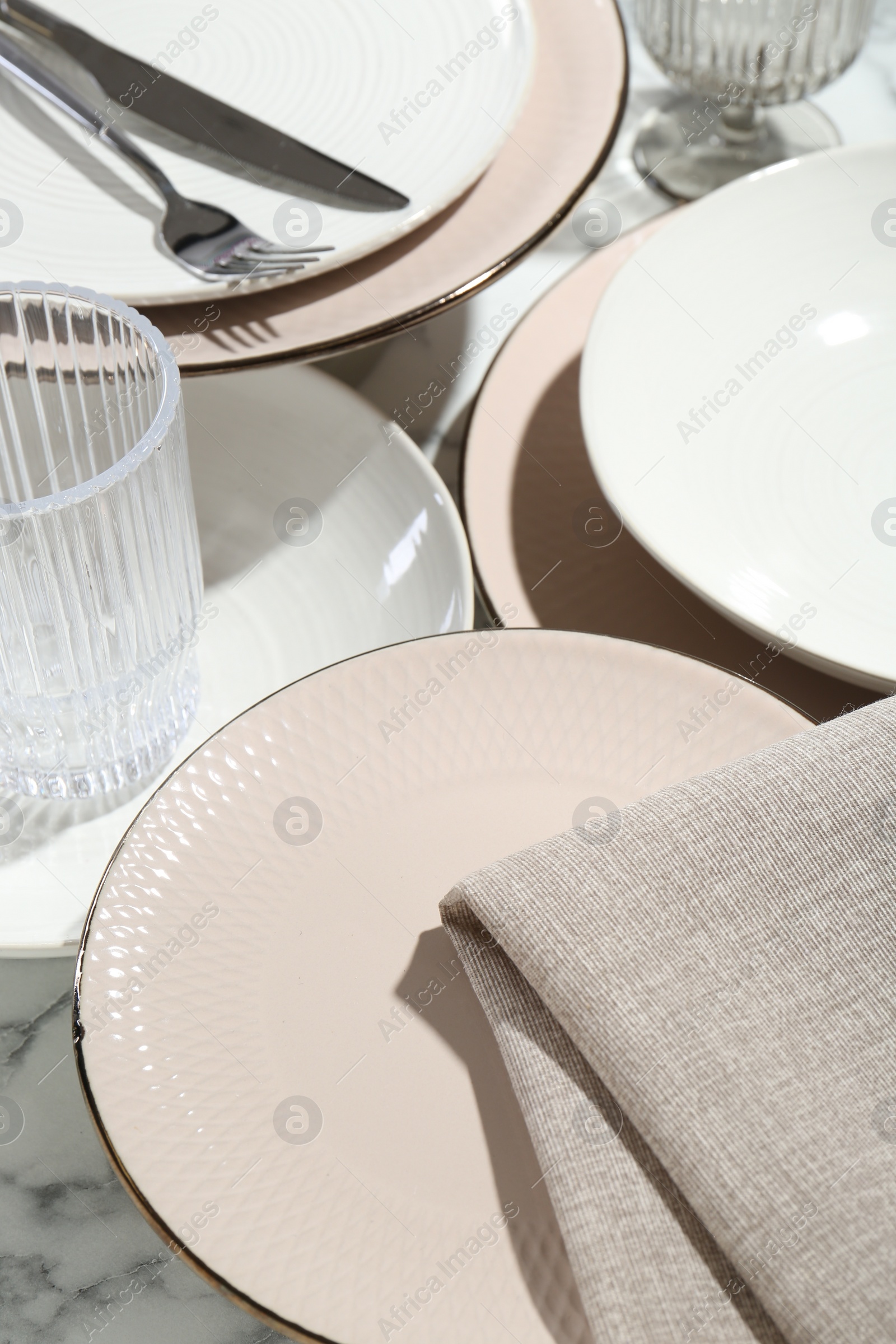 Photo of Stylish ceramic plates, cutlery, napkin and glasses on white marble table