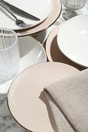 Photo of Stylish ceramic plates, cutlery, napkin and glasses on white marble table