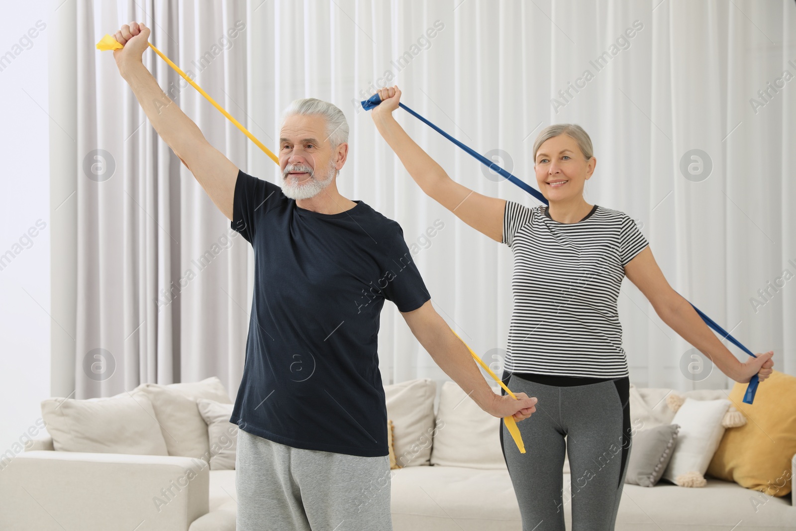 Photo of Senior couple doing exercise with fitness elastic bands at home