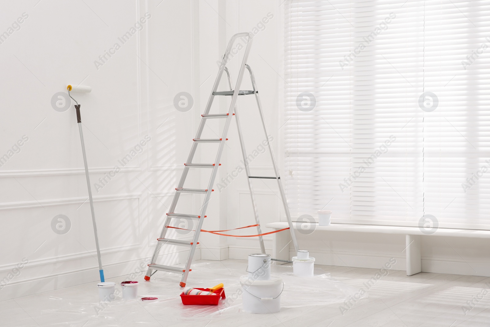 Photo of Metal stepladder, buckets of paint and renovation tools indoors