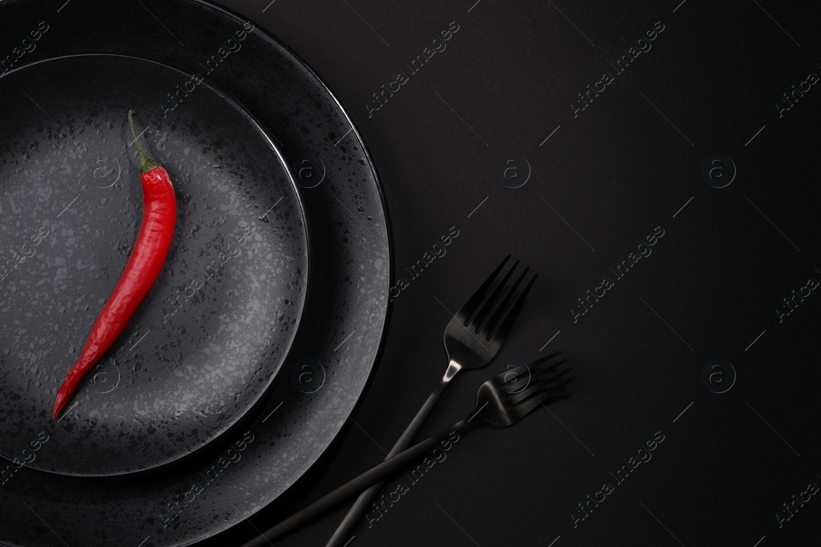 Photo of Stylish table setting. Plates, cutlery and red chilli pepper on black background, top view with space for text