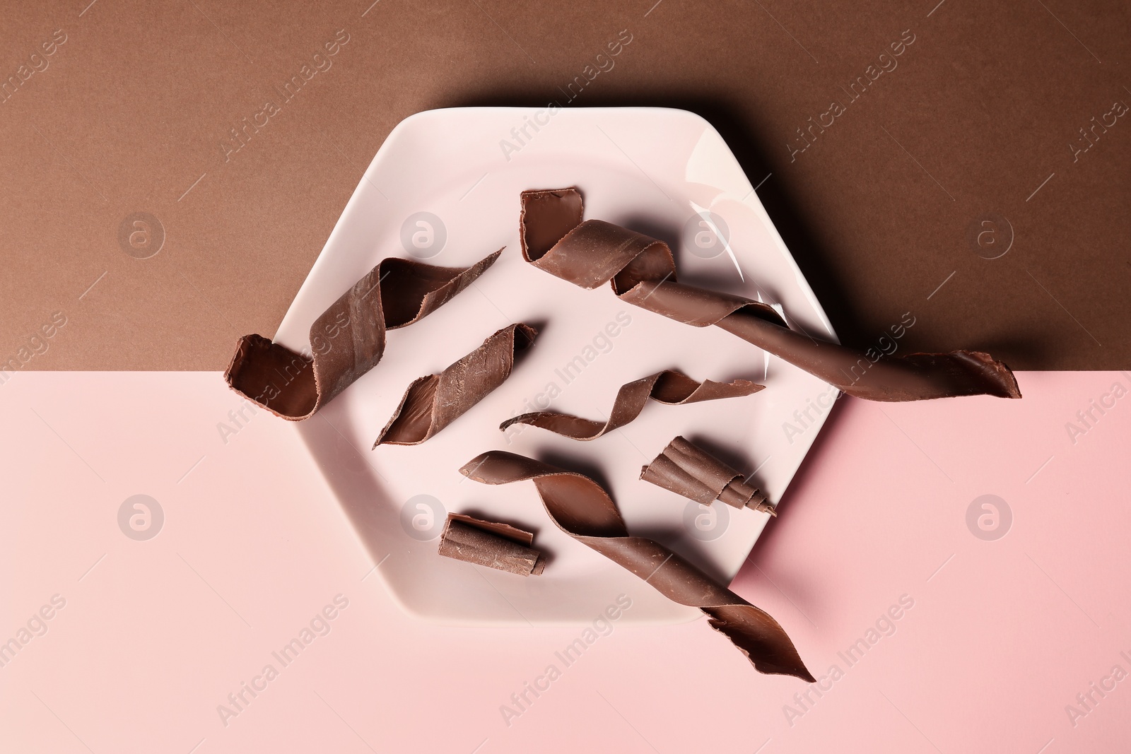 Photo of Plate with chocolate curls on color background, top view