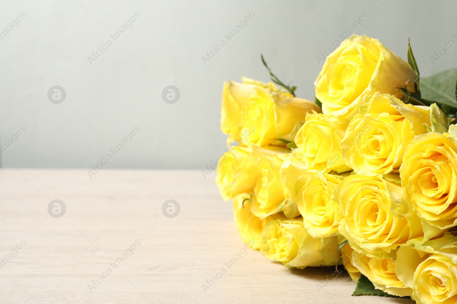 Photo of Beautiful bouquet of yellow roses on wooden table, closeup. Space for text