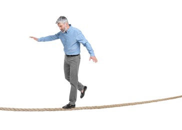 Risks and challenges of owning business. Man balancing on rope against white background