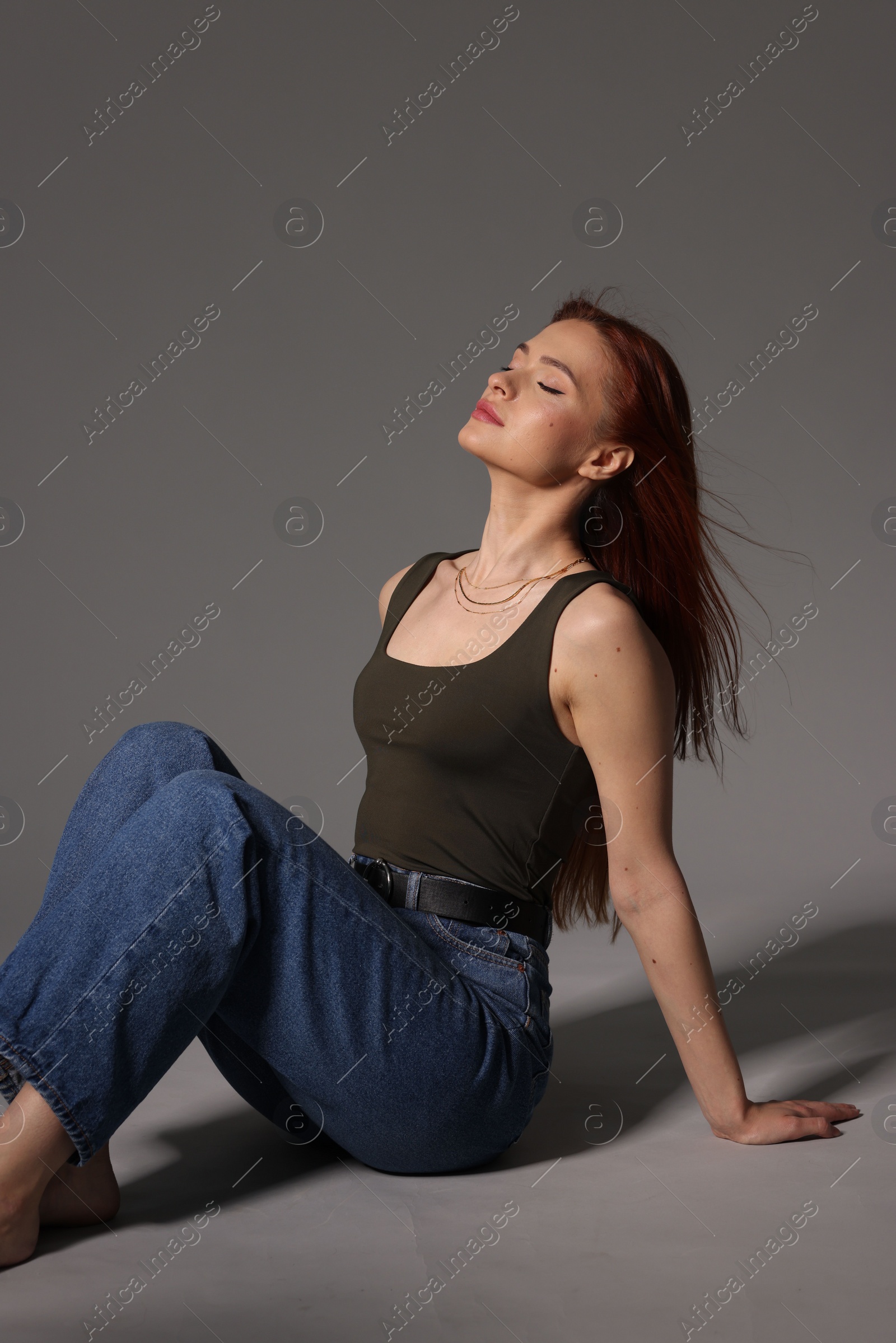 Photo of Beautiful young woman sitting on gray background