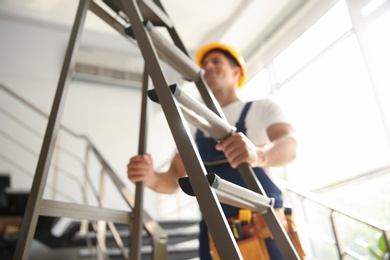 Photo of Professional builder with metal ladder on stairs, closeup