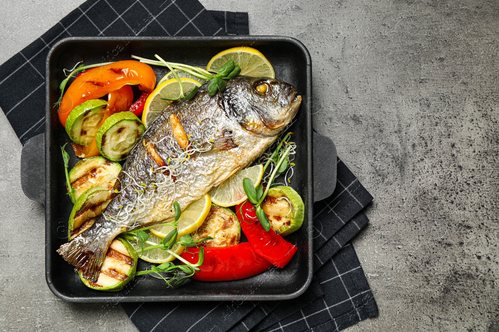 Photo of Delicious roasted fish and vegetables on grey table, top view