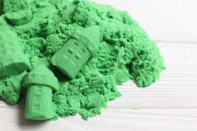 Photo of Castle figures made of green kinetic sand on white table, closeup