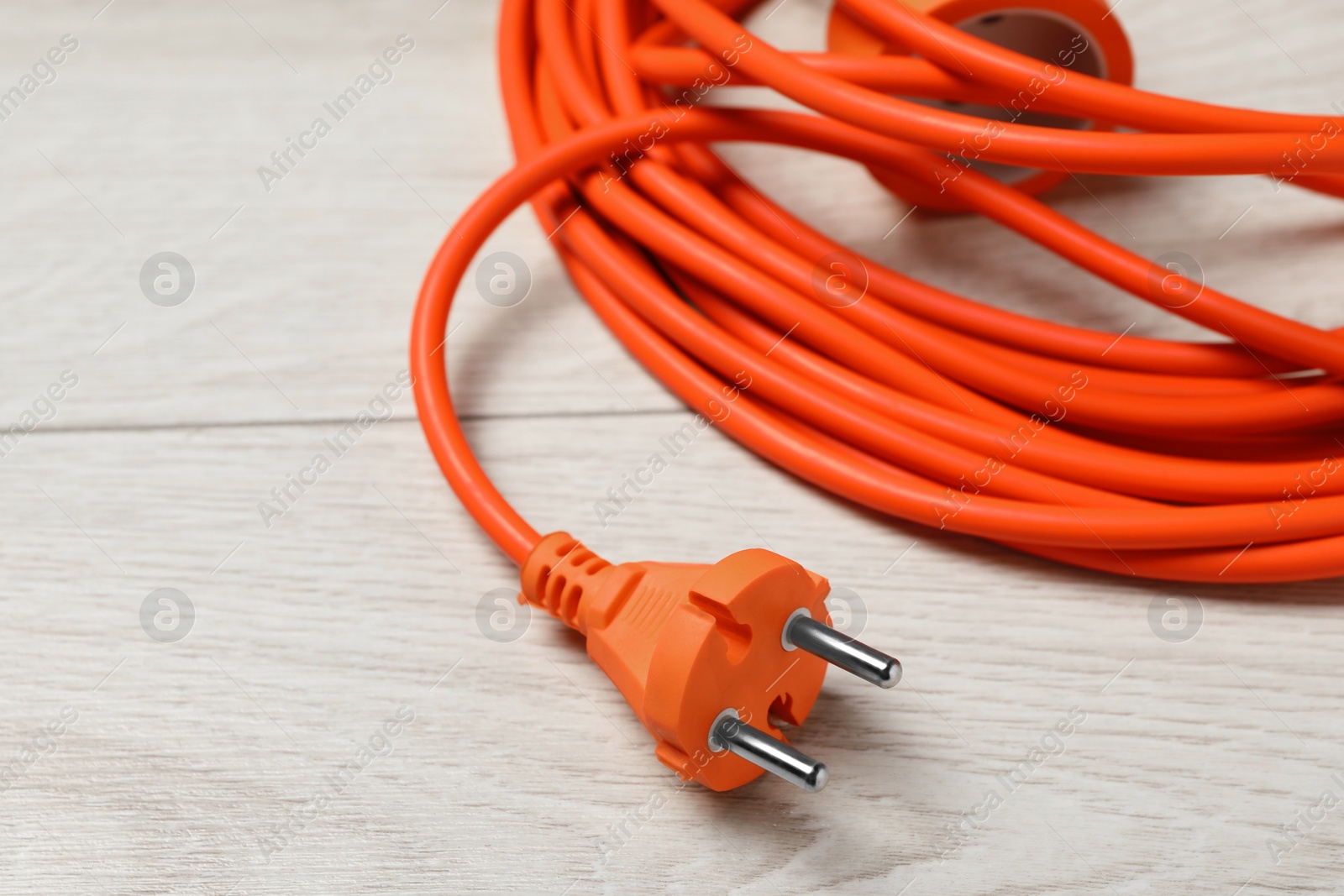 Photo of Extension cord on white wooden floor, closeup. Electrician's equipment