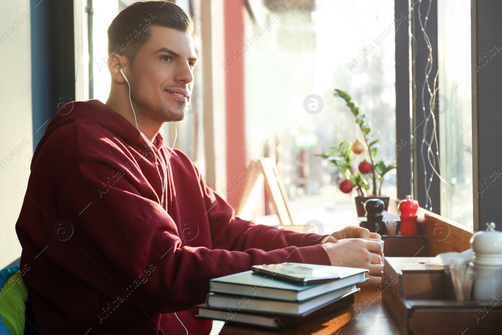 Photo of Man listening to audiobook at table in cafe