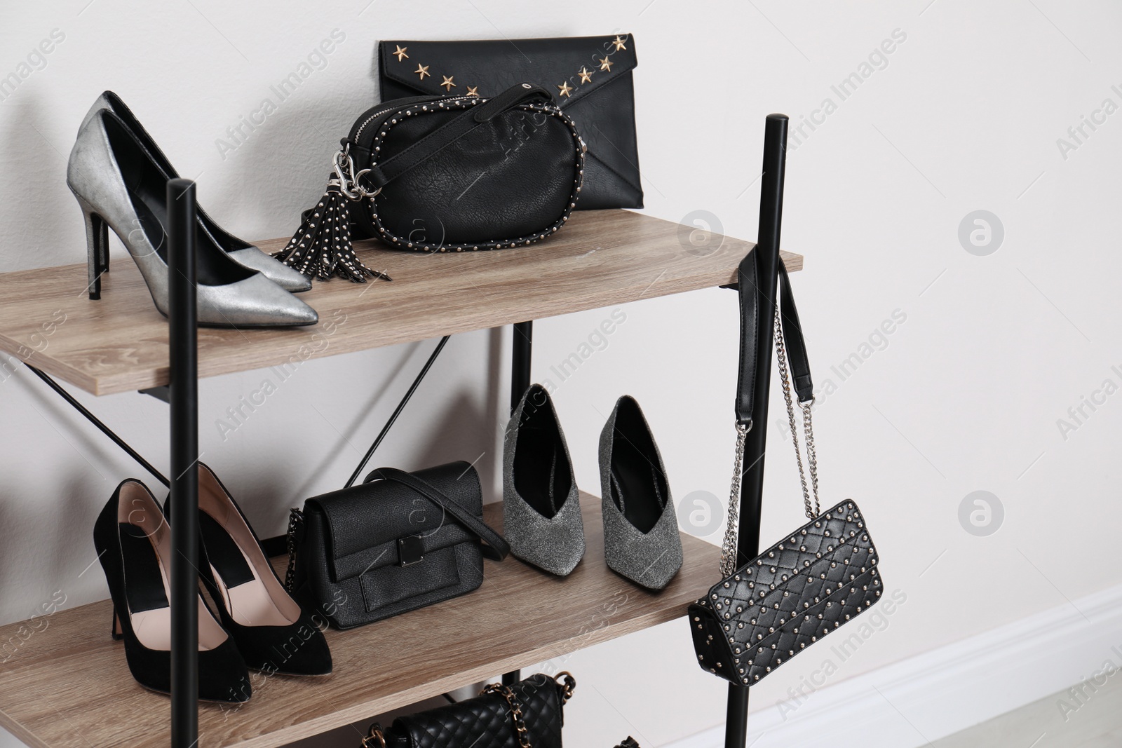 Photo of Shelving unit with stylish shoes and purses near white wall. Element of dressing room interior