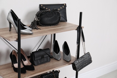 Shelving unit with stylish shoes and purses near white wall. Element of dressing room interior