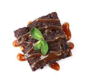 Photo of Delicious chocolate brownies with nuts, caramel sauce and fresh mint on white background, top view