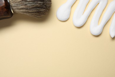 Sample of shaving foam and brush on beige background, flat lay. Space for text
