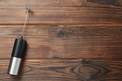 Black milk frother wand on wooden table, top view. Space for text