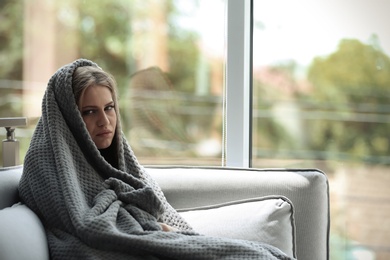 Photo of Depressed young woman sitting on sofa at home