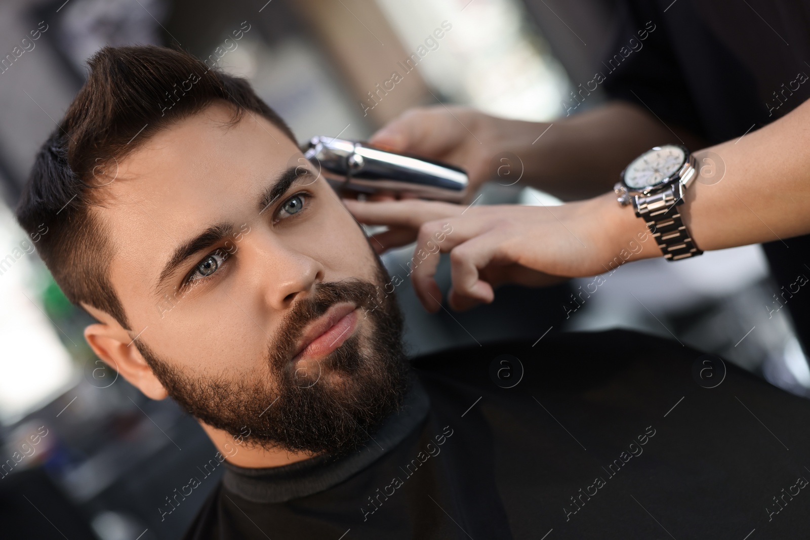 Photo of Professional hairdresser working with client in barbershop