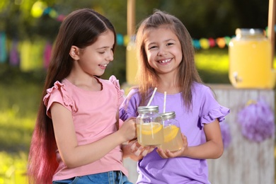 Cute little girls with natural lemonade in park. Summer refreshing drink