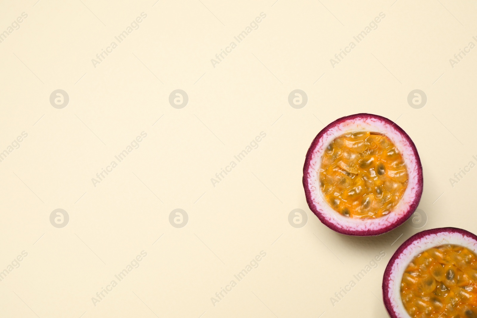 Photo of Halves of fresh ripe passion fruit (maracuya) on beige background, flat lay. Space for text