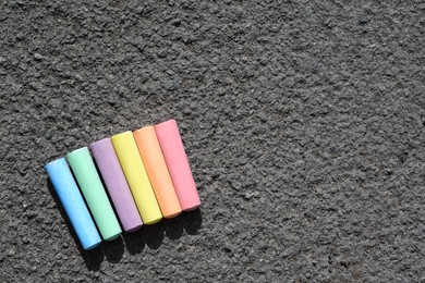 Photo of Colorful chalk sticks on asphalt, flat lay. Space for text