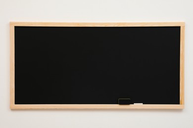 Photo of Clean black chalkboard hanging on white wall