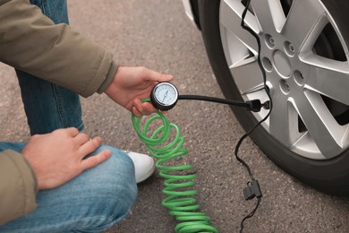 Photo of Man inflating car tire on street, closeup