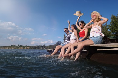 Group of friends having fun near river at summer party