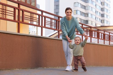 Happy nanny walking with cute little boy outdoors