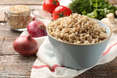 Photo of Delicious pearl barley in bowl served on wooden table, closeup