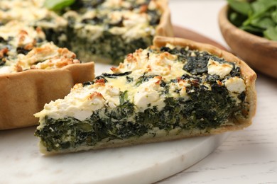 Piece of delicious homemade spinach quiche on white table, closeup