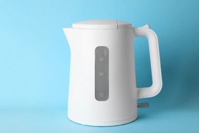 Photo of Modern electric kettle on light blue background