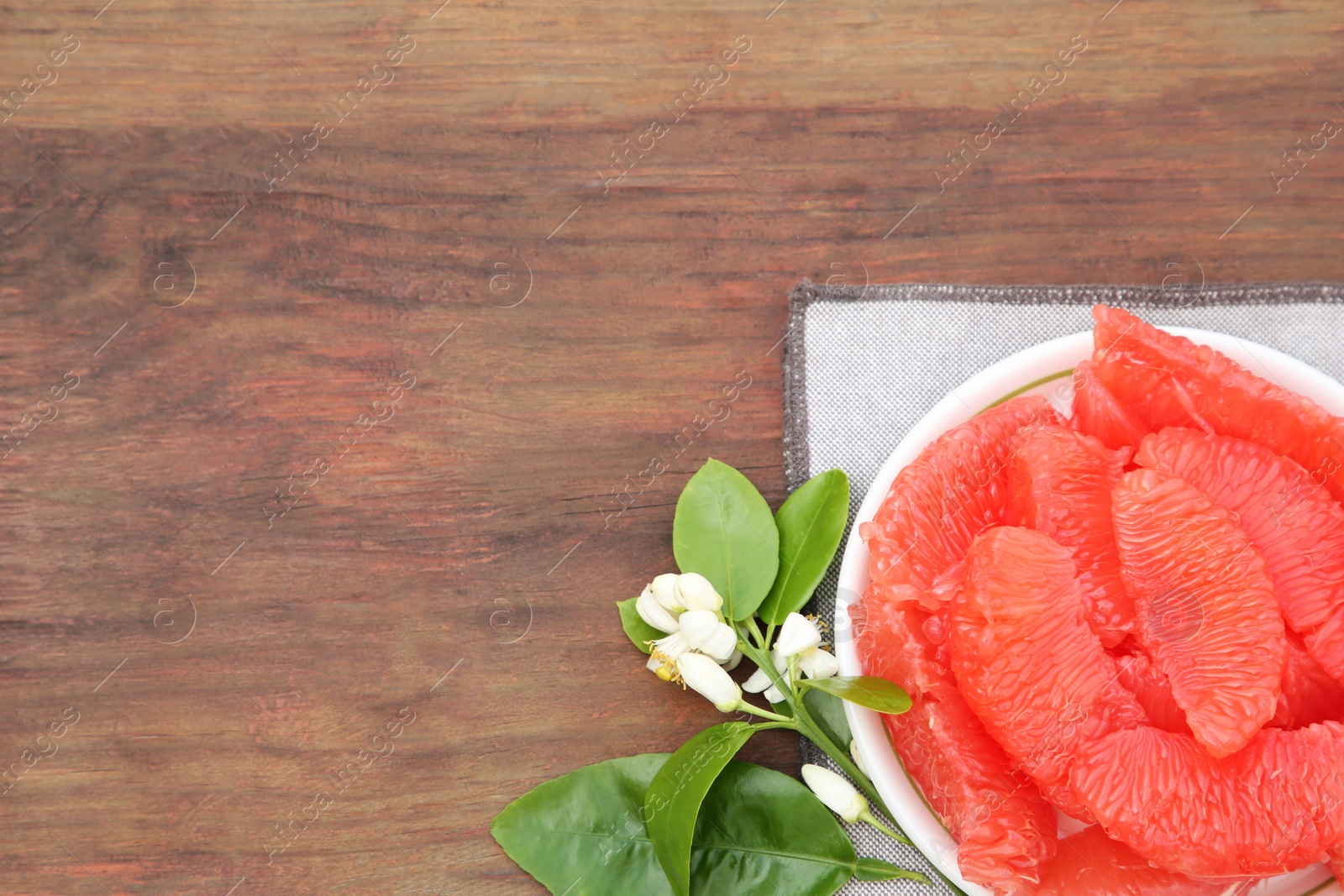 Photo of Cut fresh ripe grapefruits and green leaves on wooden table, top view. Space for text