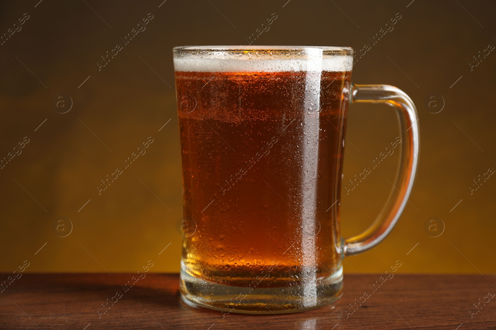 Photo of Mug with fresh beer on wooden table against dark background, closeup