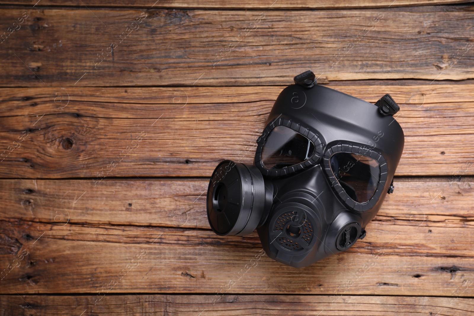 Photo of One gas mask on wooden background, top view. Space for text