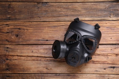 Photo of One gas mask on wooden background, top view. Space for text