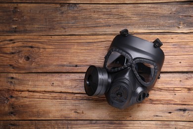 One gas mask on wooden background, top view. Space for text