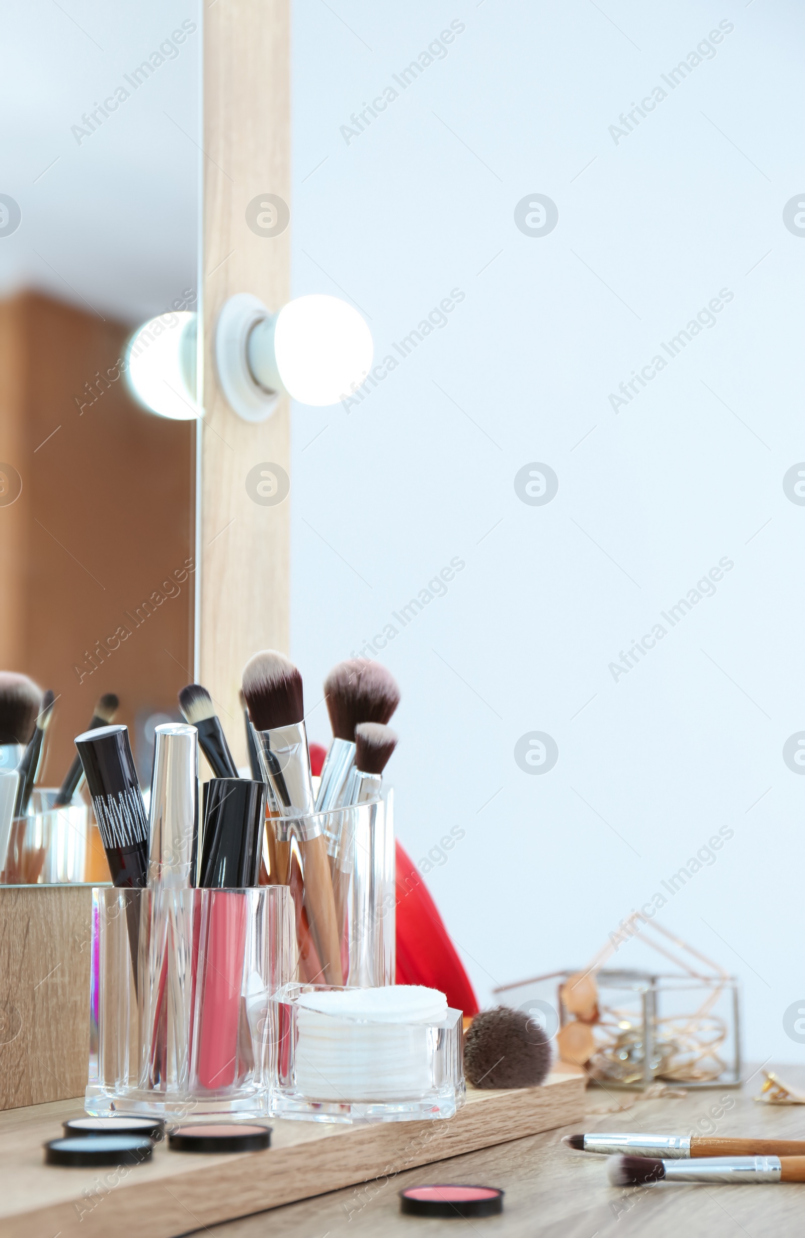 Photo of Organizer with cosmetic products for makeup on table near mirror