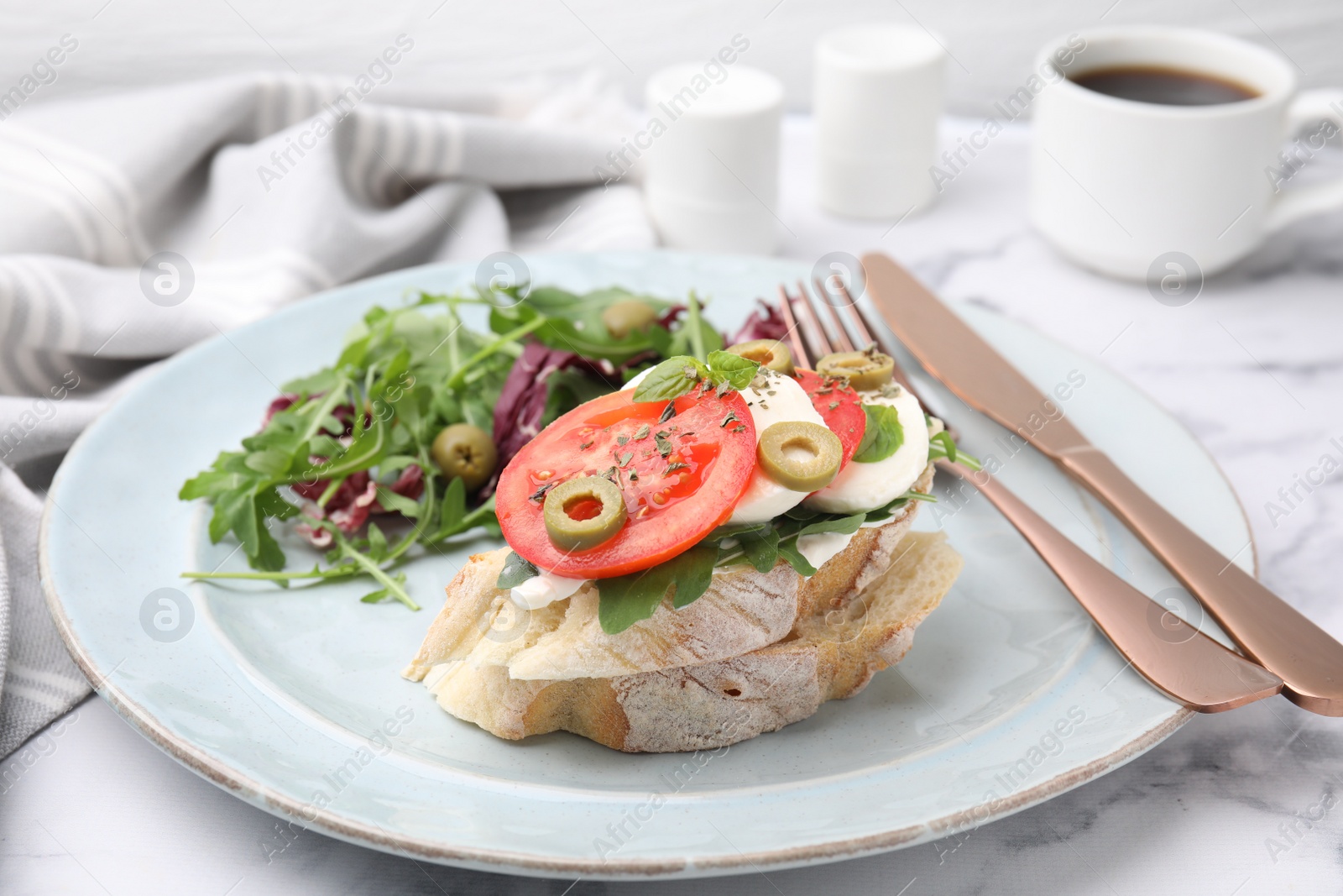 Photo of Tasty bruschetta with tomatoes, olives and mozzarella served on white marble table, closeup