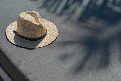 Photo of Stylish straw hat on grey sunbed outdoors, space for text